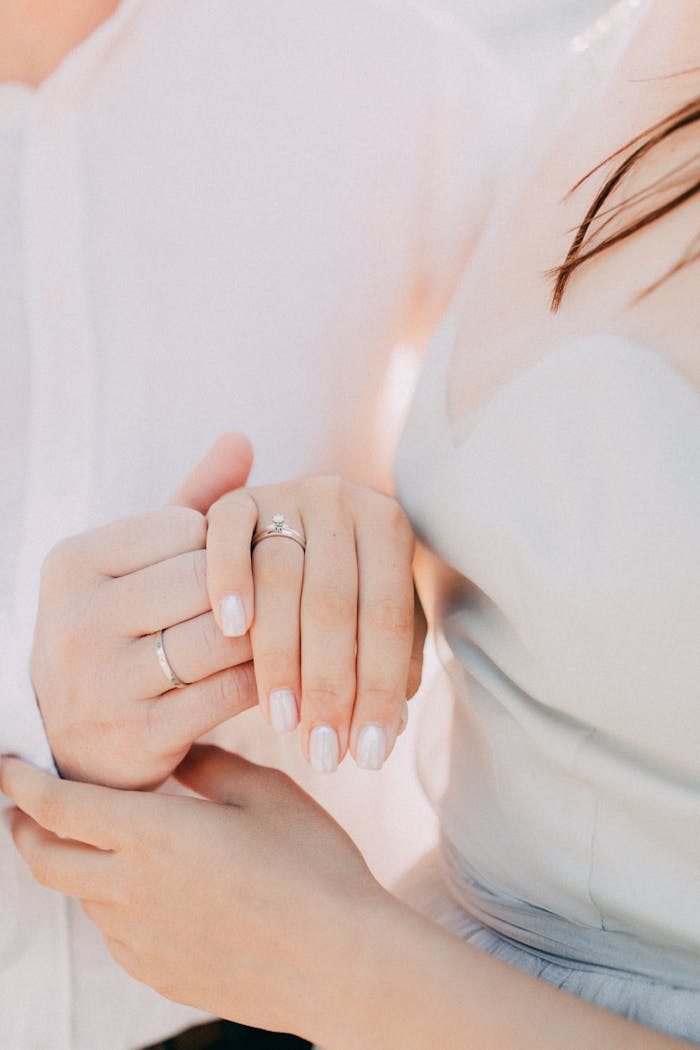 Intimate close-up of a couple's hands displaying engagement rings, symbolizing love and commitment.
